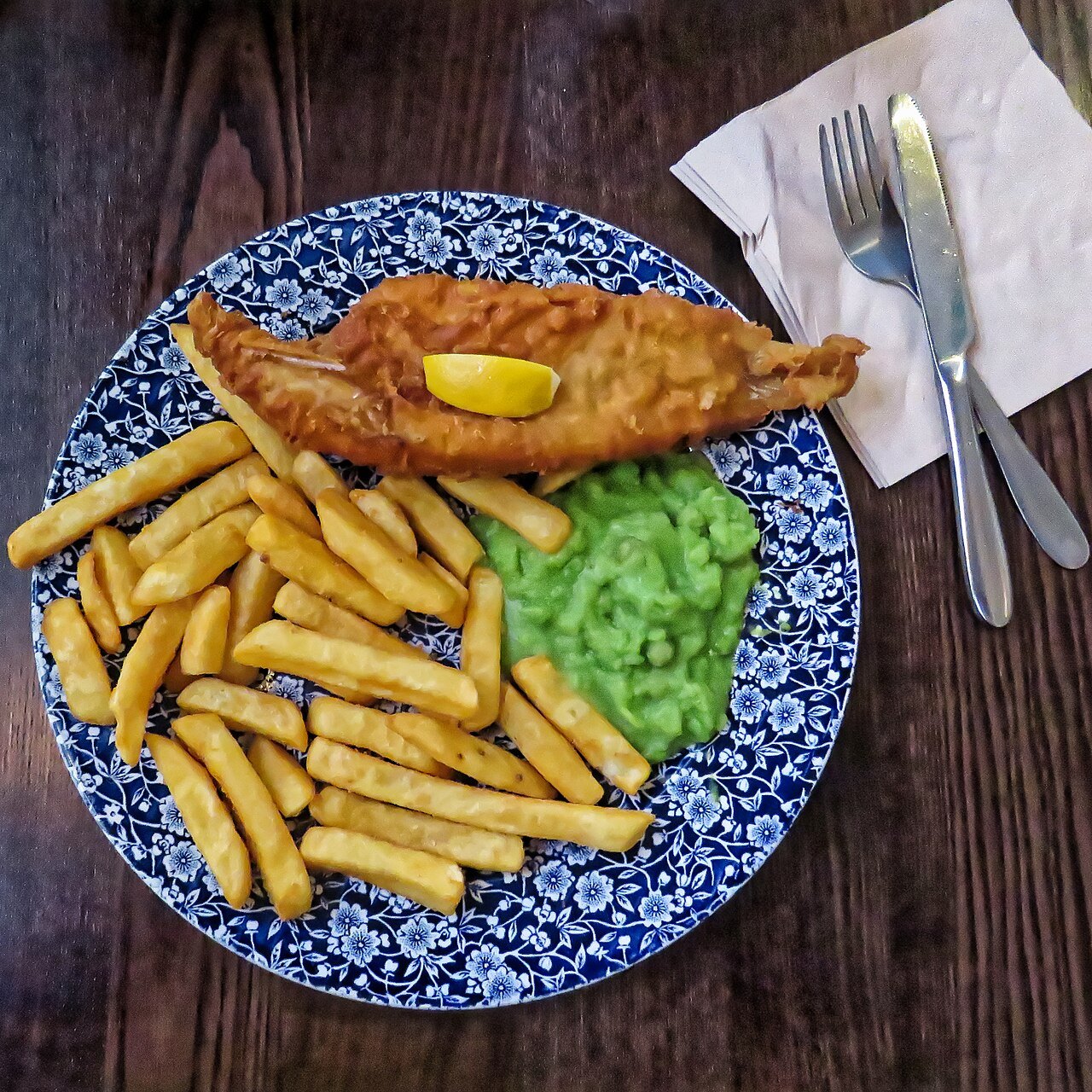 A plate of fish and chips with mushy peas