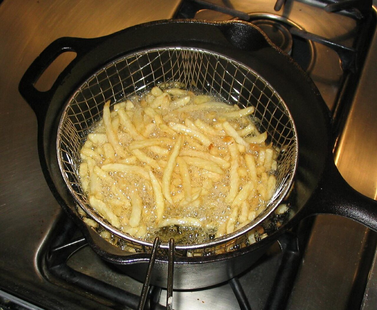French fries frying in a basket of hot oil