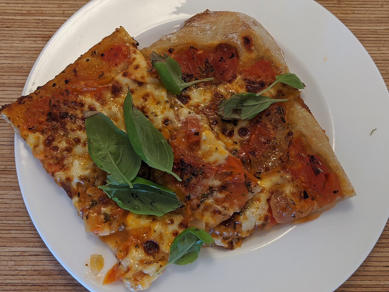 Slices of tomato, mozzarella and basil pizza
