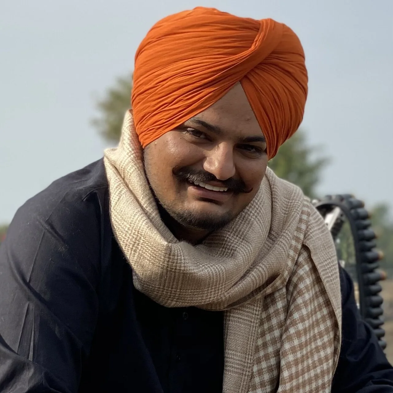 Portrait of Sidhu Moose Wala in an orange turban and checked scarf during the Moosa Jatt shoot